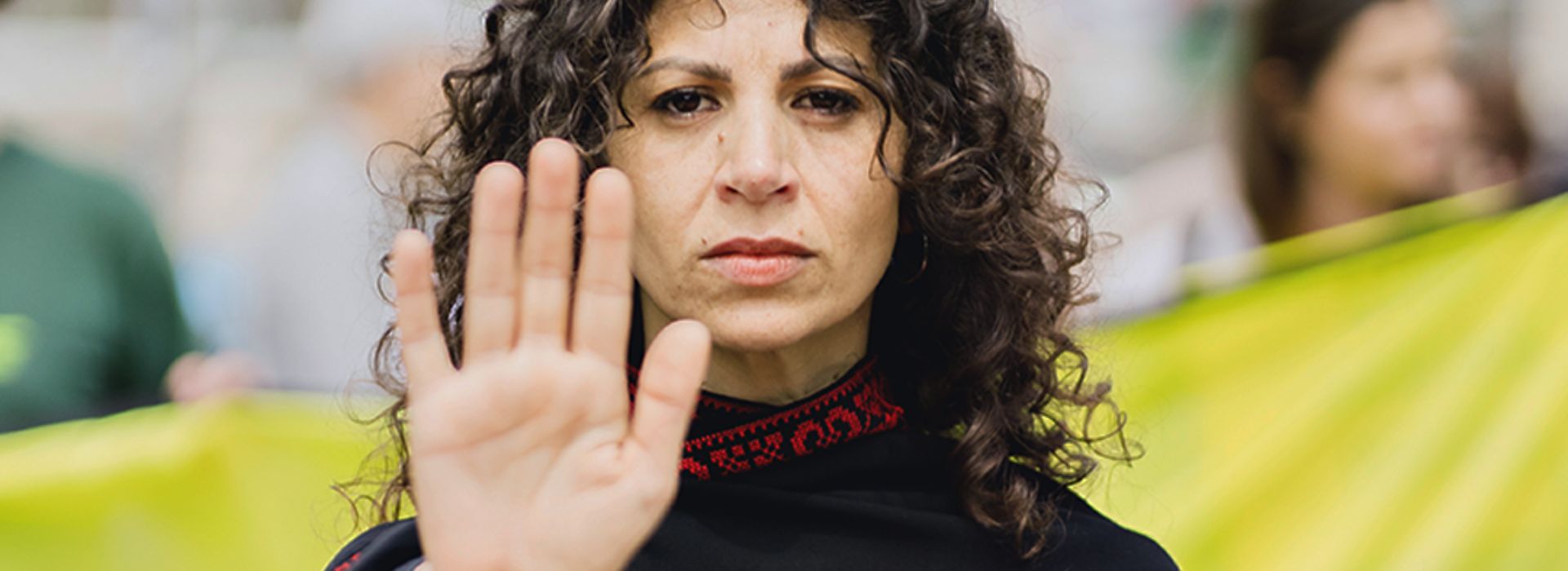 L'attrice Dalal Suleiman in primo piano con la mano a simboleggiare la richiesta di fermare il genocidio a Gaza